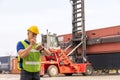 Caucasian engineer standing in front of Reach stacker vehicle in shipping yard