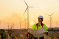 Caucasian engineer or technician man stand with holding drawiing paper and look to left side and stand in front of windmill or