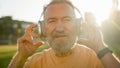 Caucasian European man pensioner at sunrise putting on headphones listening music relaxation morning workout sport