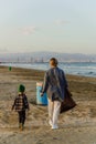 Caucasian family is collecting plastic waste on beach. Mother is teaching her son to help keep nature clean Royalty Free Stock Photo