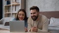 Caucasian family couple in love relaxing at home bedroom watch movie on laptop laughing talk online video call having Royalty Free Stock Photo