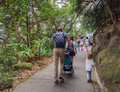 A Caucasian family hiking with kids along Lugard road, Victoria Peak, Hong Kong in forest during covid-19. man walk with carrying