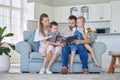 Caucasian family reading a book together on the couch at home. Mother and father teaching their little son and daughter Royalty Free Stock Photo