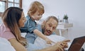 Caucasian family of three using laptop while lying on bed together, browsing internet or watching movie Royalty Free Stock Photo