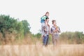 Caucasian family walking across field with young child on her fathers shoulders with the wife holding a bouquet of flowers