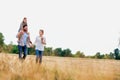 Young Caucasian family walking across field with young child on her fathers shoulders with the wife holding a bouquet of flowers