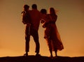 Caucasian family watching the sunset standing on a rock together on the beach from behind. Parents spending time with Royalty Free Stock Photo