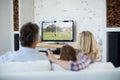 Caucasian family watching tv with football match on screen