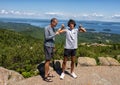 Caucasian father and Amerasian teenage son standing atop Cadillac Mountain with Bar Harbor, Maine in the background.