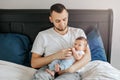 Caucasian father holding newborn infant baby. Man parent lying with child daughter son in bedroom. Authentic lifestyle candid home Royalty Free Stock Photo