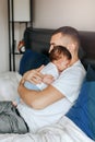 Caucasian father holding newborn infant baby. Man parent lying with child daughter son in bedroom. Authentic lifestyle candid home Royalty Free Stock Photo