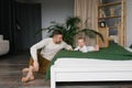 Caucasian father playing with cute baby boy on the bed at home. Happy family, attractive handsome dad looks at his little son lyin Royalty Free Stock Photo