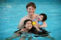 Caucasian father in pool with biracial children, holding disabled son