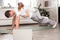 Caucasian father and small daughter in casual clothes do pushup pressup exercise on carpet on warm floor in living room, sporty