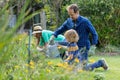 Caucasian father and son in garden watering plants and gardening with their family Royalty Free Stock Photo