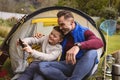 Caucasian father and son taking a selfie while sitting in a tent in the garden Royalty Free Stock Photo