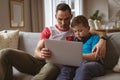 Caucasian father and son using laptop sitting on the couch at home Royalty Free Stock Photo