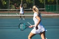 Caucasian female athlete running while playing tennis game with african american competitor at court