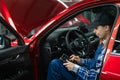 Caucasian female auto mechanic uses a special computer to diagnose faults.