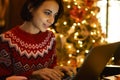 Caucasian female blogger in red winter sweater texting and reading connected to 4g wireless in xmass interior