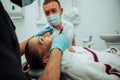 Caucasian female client lying on doctors bed while male nurse cleans teeth