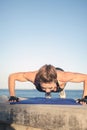 Caucasian female fitness model performing push up exercise outdoor at sea promenade