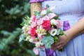 Caucasian female guest or bridesmaid wearing a lilac summer dress which shows a lovely baby bump and holding a wedding bouquet Royalty Free Stock Photo