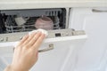 Caucasian female hand cleaning open dishwasher with cloth in kitchen setting Royalty Free Stock Photo