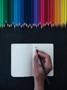 Caucasian female hand writing on notebook, colorful pencils background Royalty Free Stock Photo