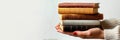 Caucasian female hands holding a stack of vintage books. Concept of education diversity, reading materials, and Royalty Free Stock Photo