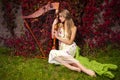 caucasian female harpist posing with harp against ivy wall outdoor