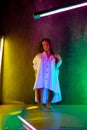 Caucasian female inclusive model posing on studio background in neon light
