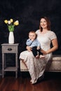 Caucasian female parent and son baby boy sitting together on couch indoors. Happy mother day holiday