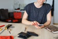 Caucasian female person looking for ideas by smartphone near handmade notebook at leather atelier.