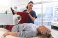 Caucasian female physiotherapist and senior woman with artificial leg stretching at hospital Royalty Free Stock Photo