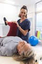 Caucasian female physiotherapist and senior woman stretching leg at hospital Royalty Free Stock Photo