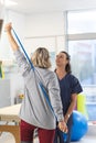 Caucasian female physiotherapist and senior woman using exercise band stretching arms Royalty Free Stock Photo