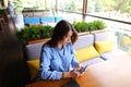 Caucasian female student sitting at cafe with notebook on table and using smartphone.