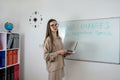 Caucasian female student standing near whiteboard explains the rules in classroom Royalty Free Stock Photo