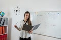 Caucasian female student standing near whiteboard explains the rules in classroom Royalty Free Stock Photo