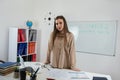 Caucasian female student standing near whiteboard explains the rules in classroom Royalty Free Stock Photo