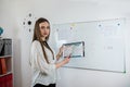 Caucasian female student standing near whiteboard explains the rules in classroom Royalty Free Stock Photo