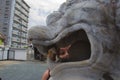 Caucasian female tourist posing, looking through mouth of a white marble dragon statue in Japan Royalty Free Stock Photo