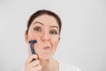 Caucasian funny woman shaves her face with a straight razor on a white background. Copy space. Royalty Free Stock Photo