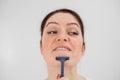 Caucasian funny woman shaves her face with a straight razor on a white background. Copy space. Royalty Free Stock Photo