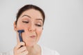 Caucasian funny woman shaves her face with a straight razor on a white background. Copy space. Royalty Free Stock Photo