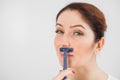 Caucasian funny woman shaves her face with a straight razor on a white background. Copy space. Royalty Free Stock Photo