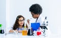 Caucasian girl and African black boy studying Science and doing experiment together in classroom at school. Education and Royalty Free Stock Photo