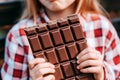 Caucasian girl close up holding chocolate bar in hands