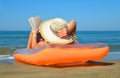 Caucasian girl with hat lying on inflatable mattress and reading a book on the beach. Royalty Free Stock Photo